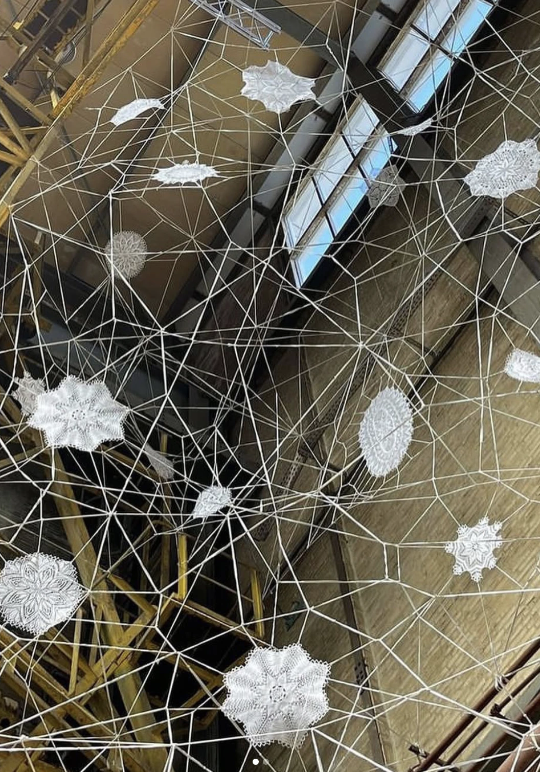 Œuvre en volume réalisée avec de la ficelle blanche et des broderies reliées entre elles par la ficelle.