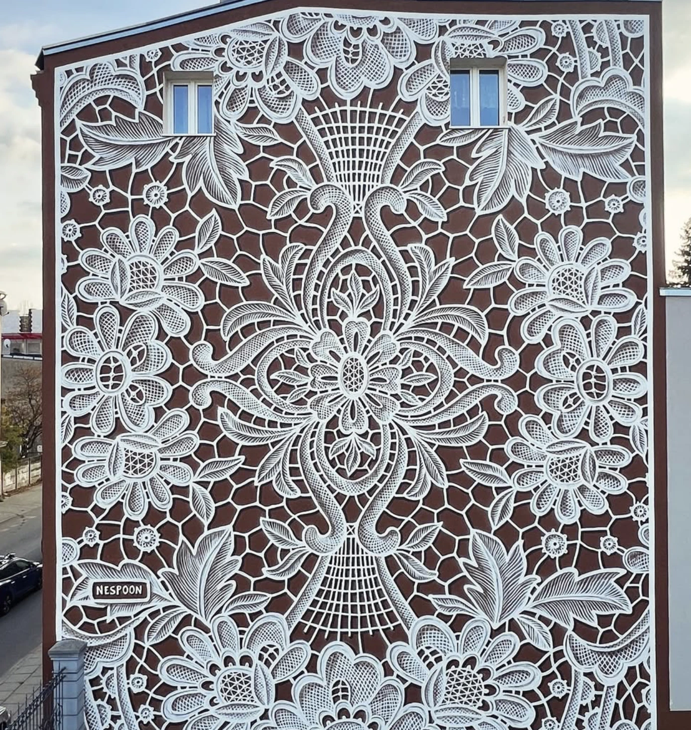 Fresque sur un mur représentant une broderie blanche de fleurs et de feuilles.