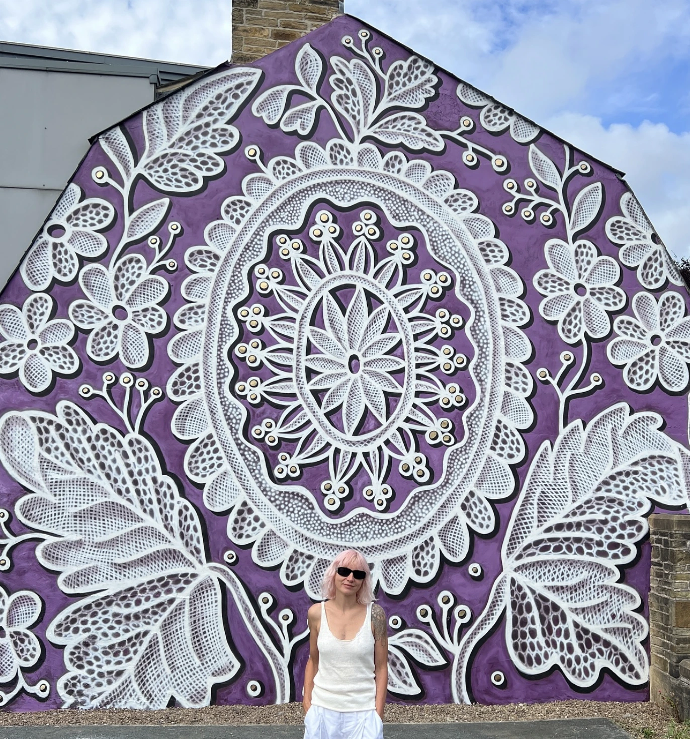 Fresque sur fond violet, peinte comme une broderie, avec des fleurs brodées, des feuilles et un cercle de style mandala au centre.