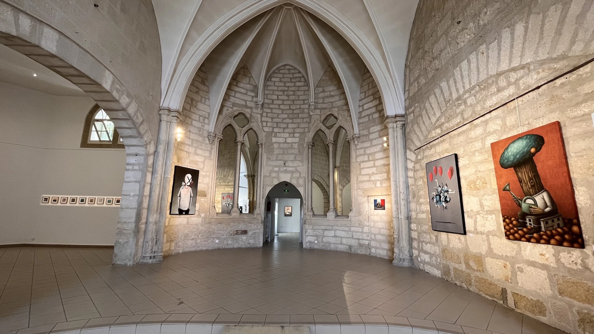 On découvre l'architecture d'une pièce avec des voutes et des miroirs des oeuvres accrochées aux murs.