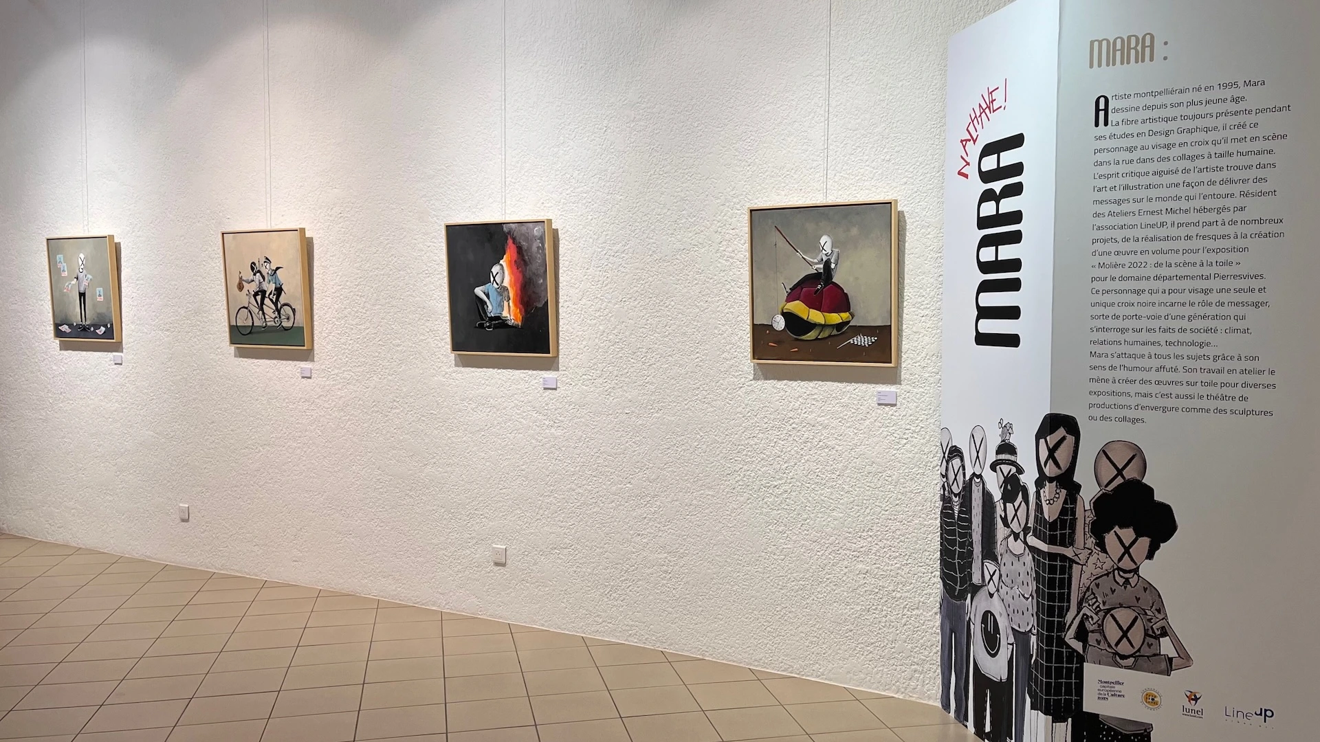 Suite de 4 toiles de format carré exposés sur un mur blanc, un paravent avec le visuel de l'artiste et un texte sur la droite de l'image.