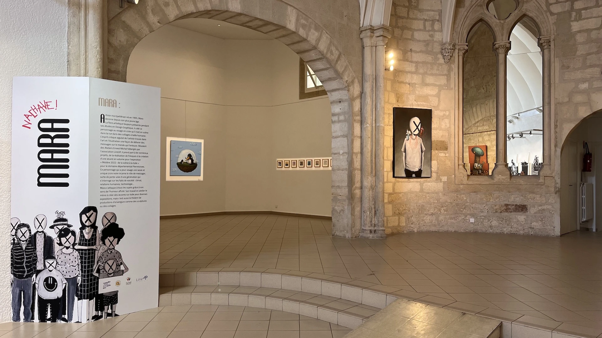 On découvre l'architecture d'une pièce avec des voutes et des miroirs, le paravent de l'artiste sur la gauche et des oeuvres accrochées aux murs.