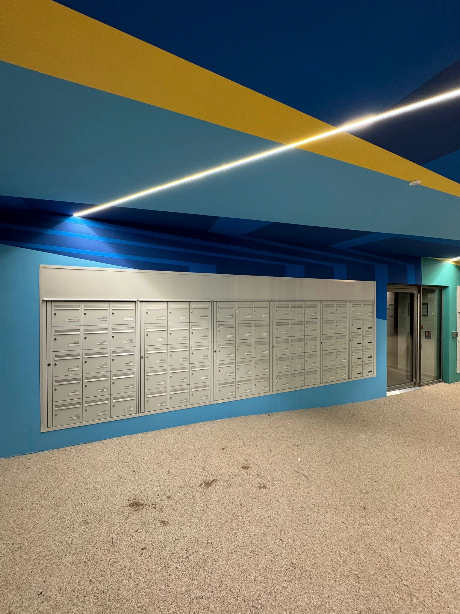 Vue d'un angle du mur avec les boîtes aux lettres et la fresque autour.