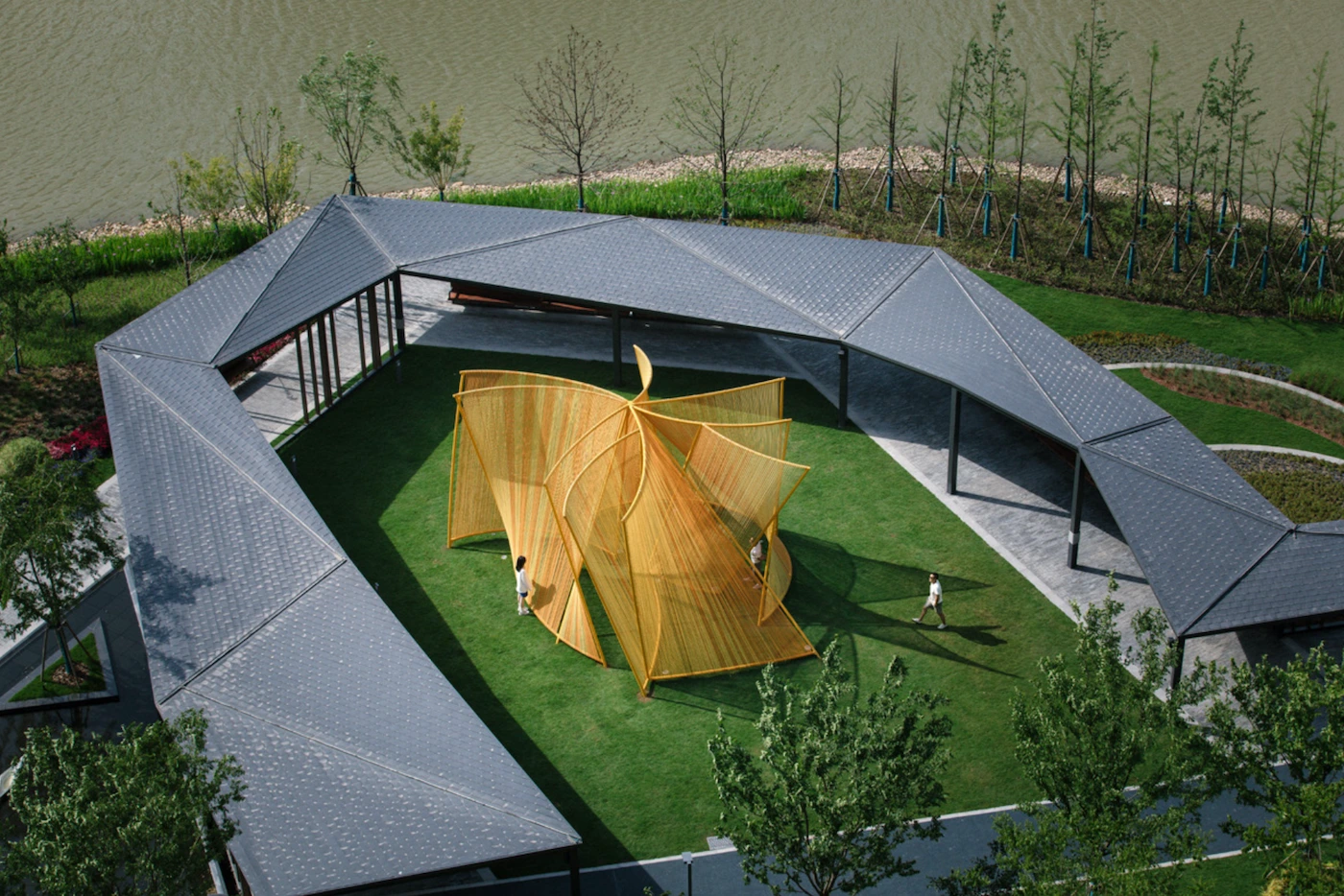 Installation architecturale en plein air avec tente jaune et toitures noires
