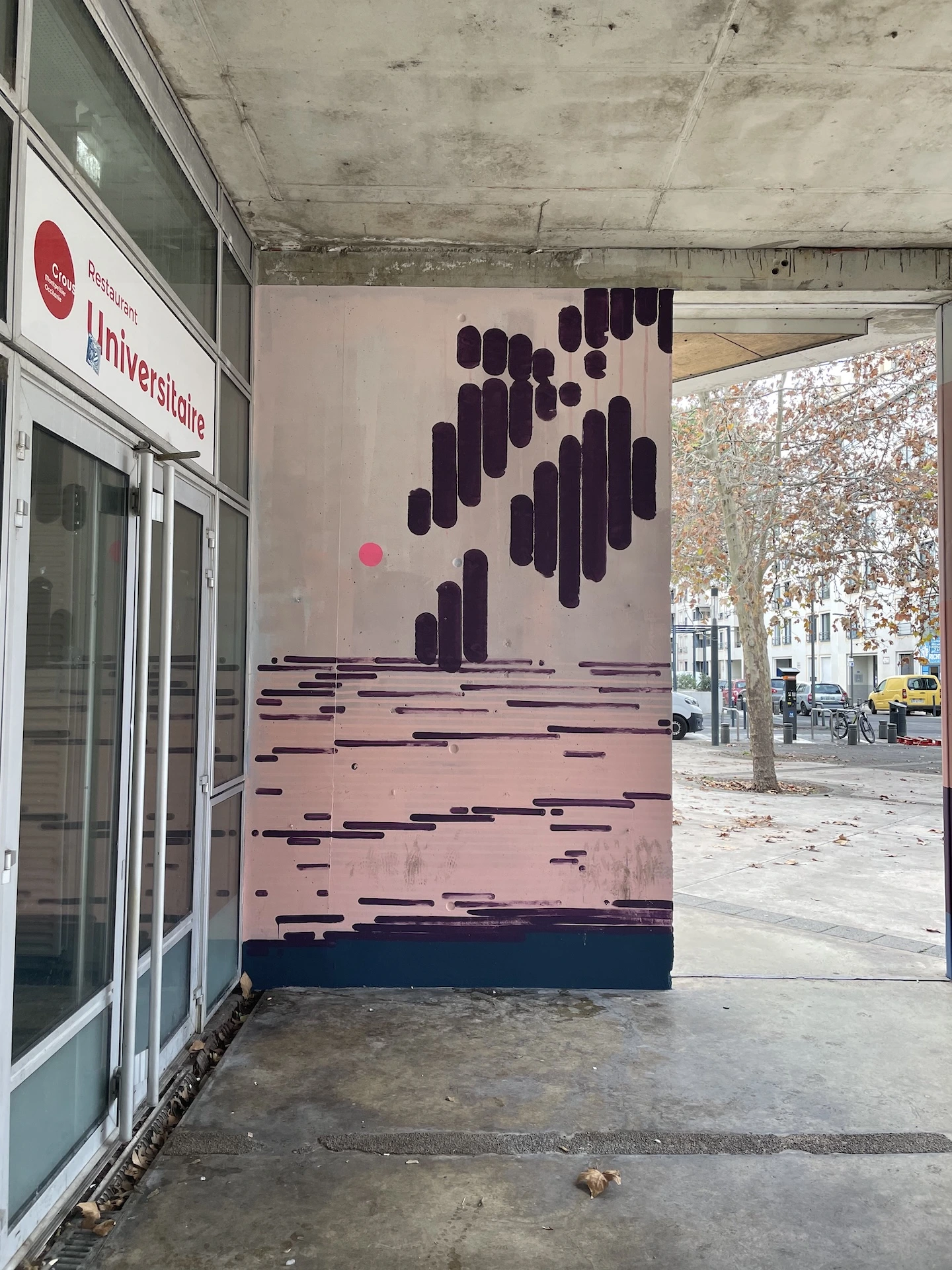 Détail d’une fresque abstraite aux teintes violettes et roses, peinte sous un auvent du restaurant universitaire