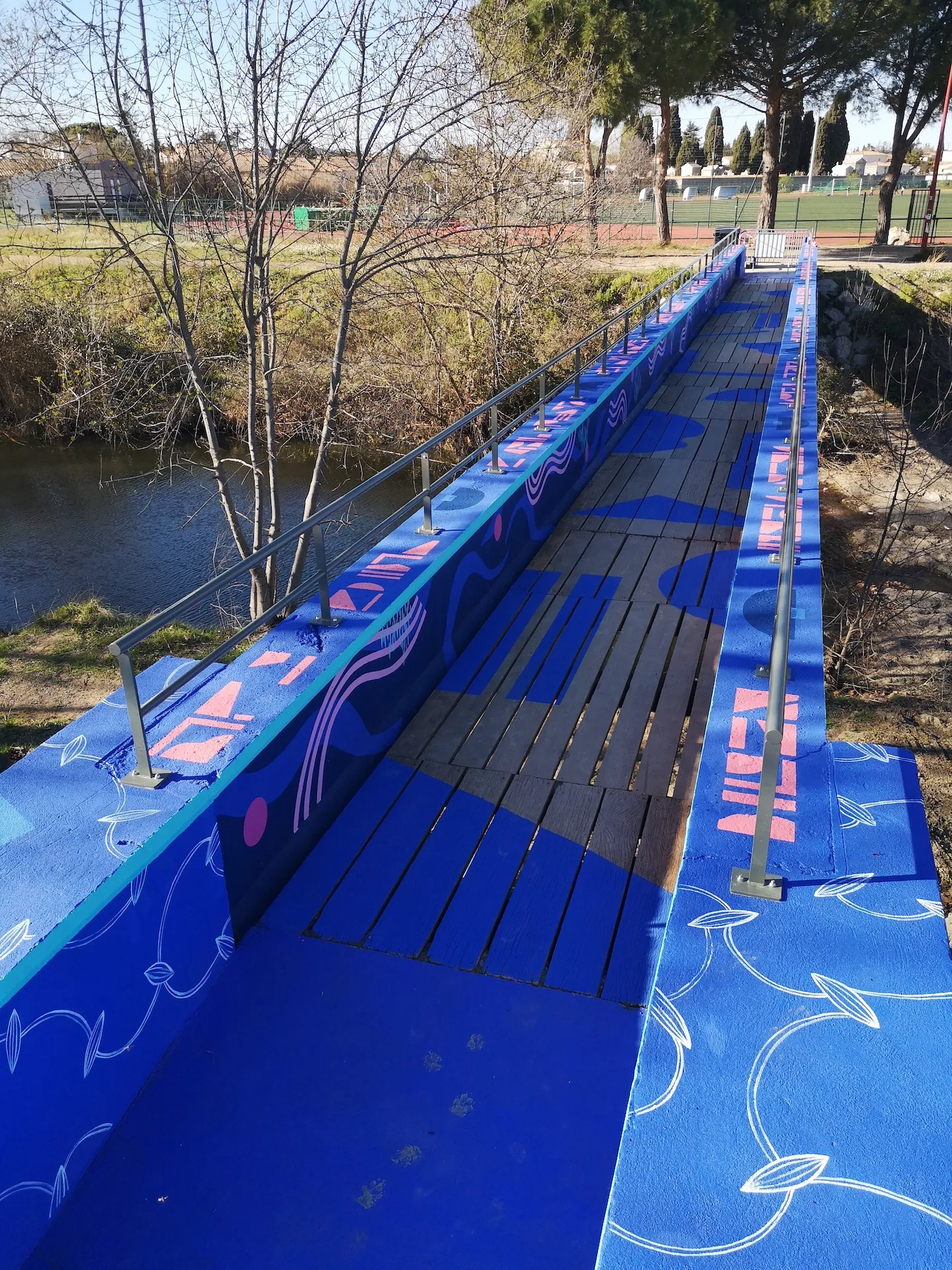 Photo d'une passerelle peinte en bleu avec des motifs en rose.