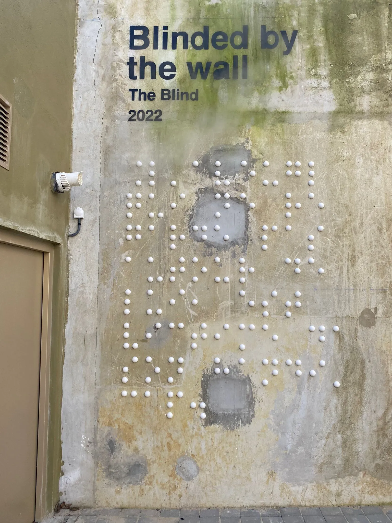 Vue de près d'une partie du mur avec les lettres en braille en volume.