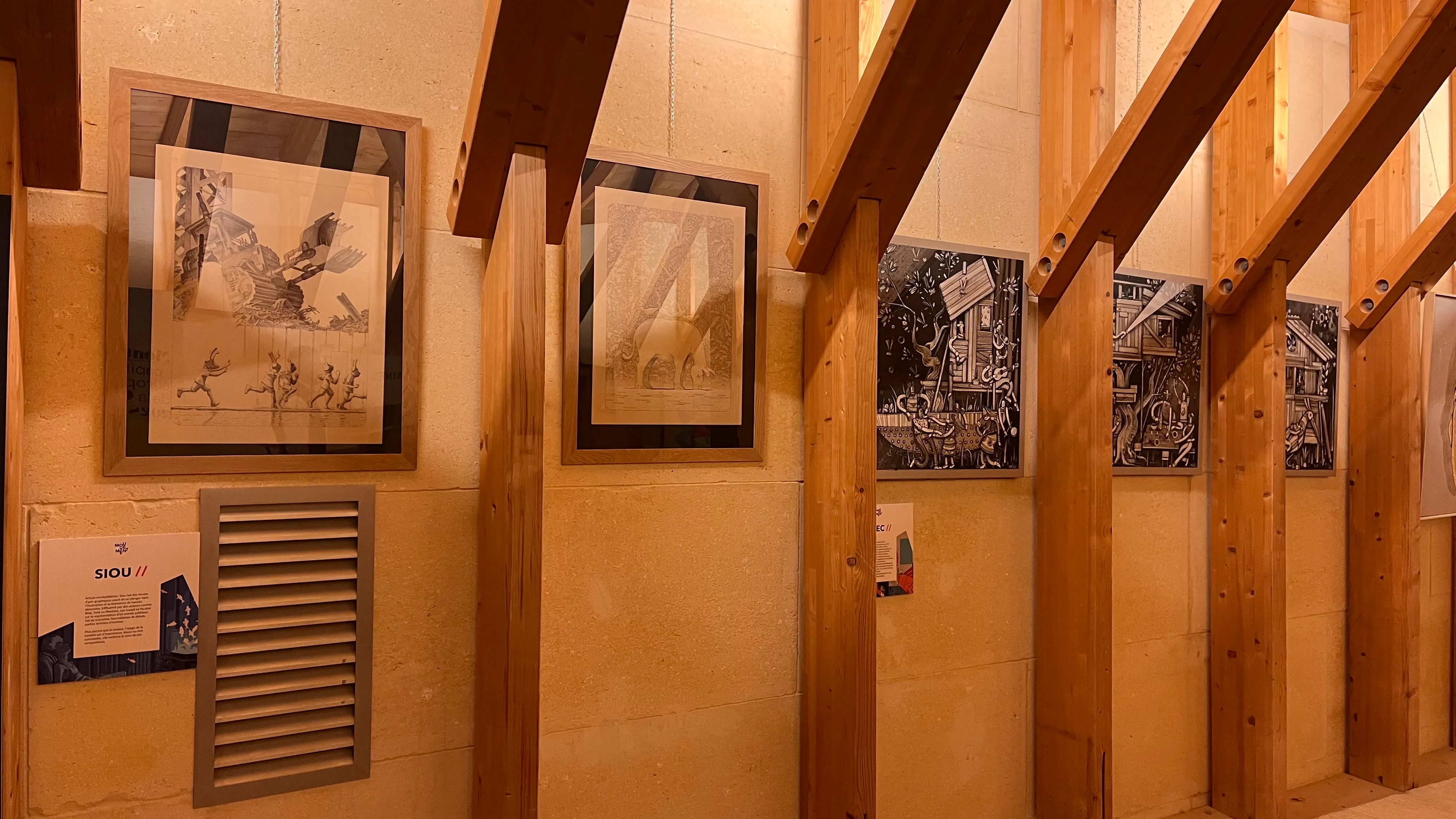 Détail d'une exposition d'oeuvres en noir et blanc accrochées dans un espace boisé.