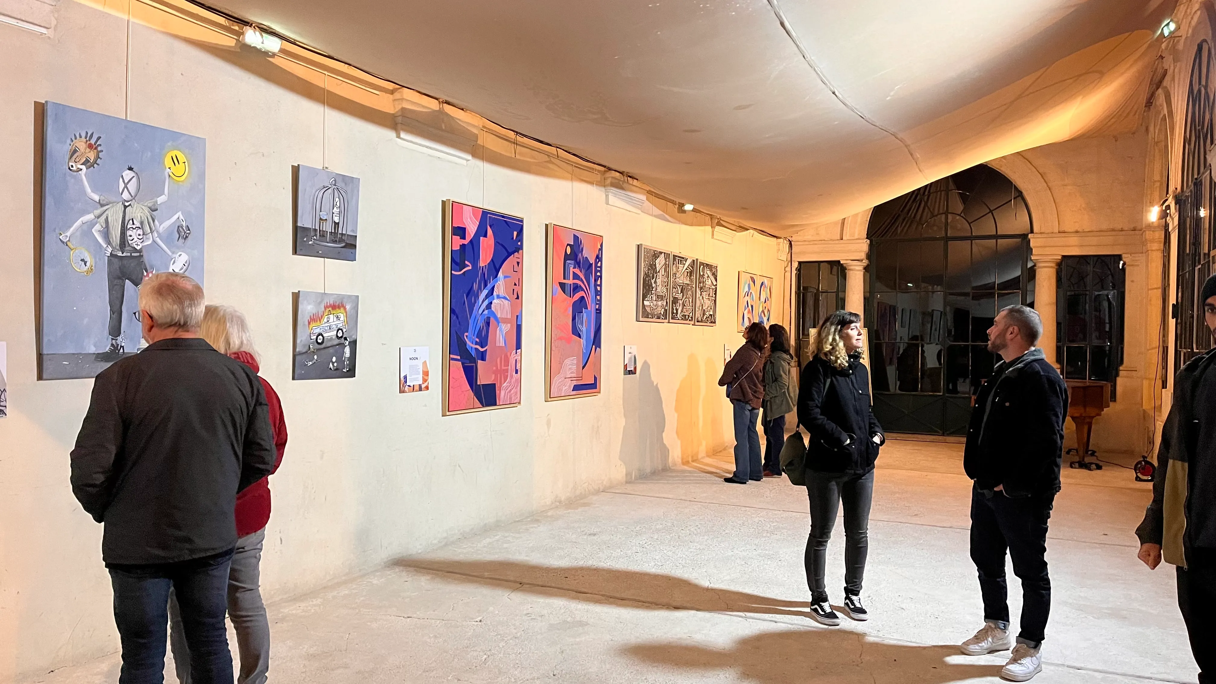 Visiteurs observant les œuvres exposées dans un espace lumineux à voûte blanche.