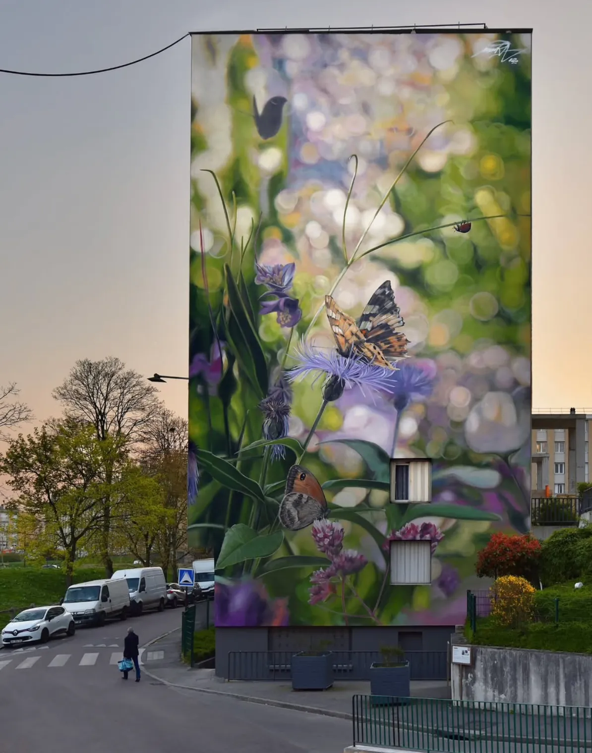 Fresque de grande taille représentant des fleurs et des insectes peinte sur un immeuble résidentiel.