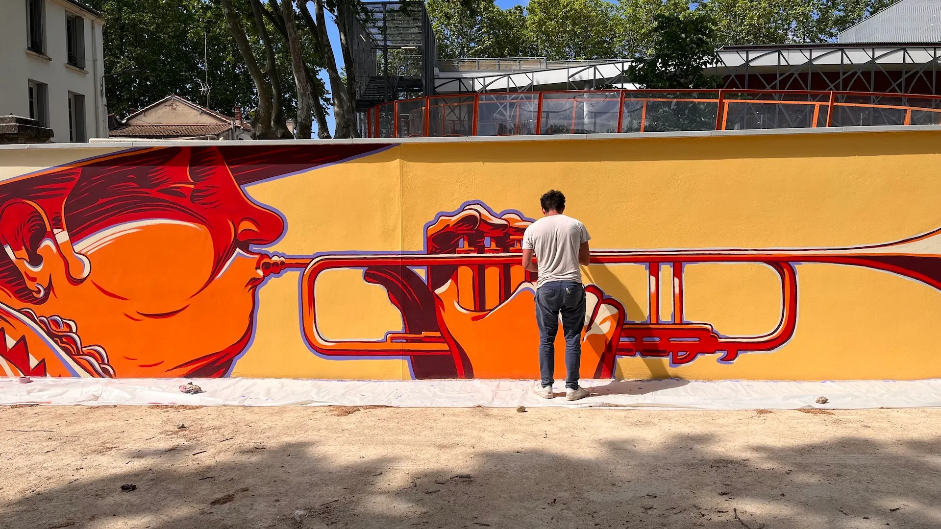 Personne assise devant une fresque représentant deux visages rouges reliés par une lunette de visée.
