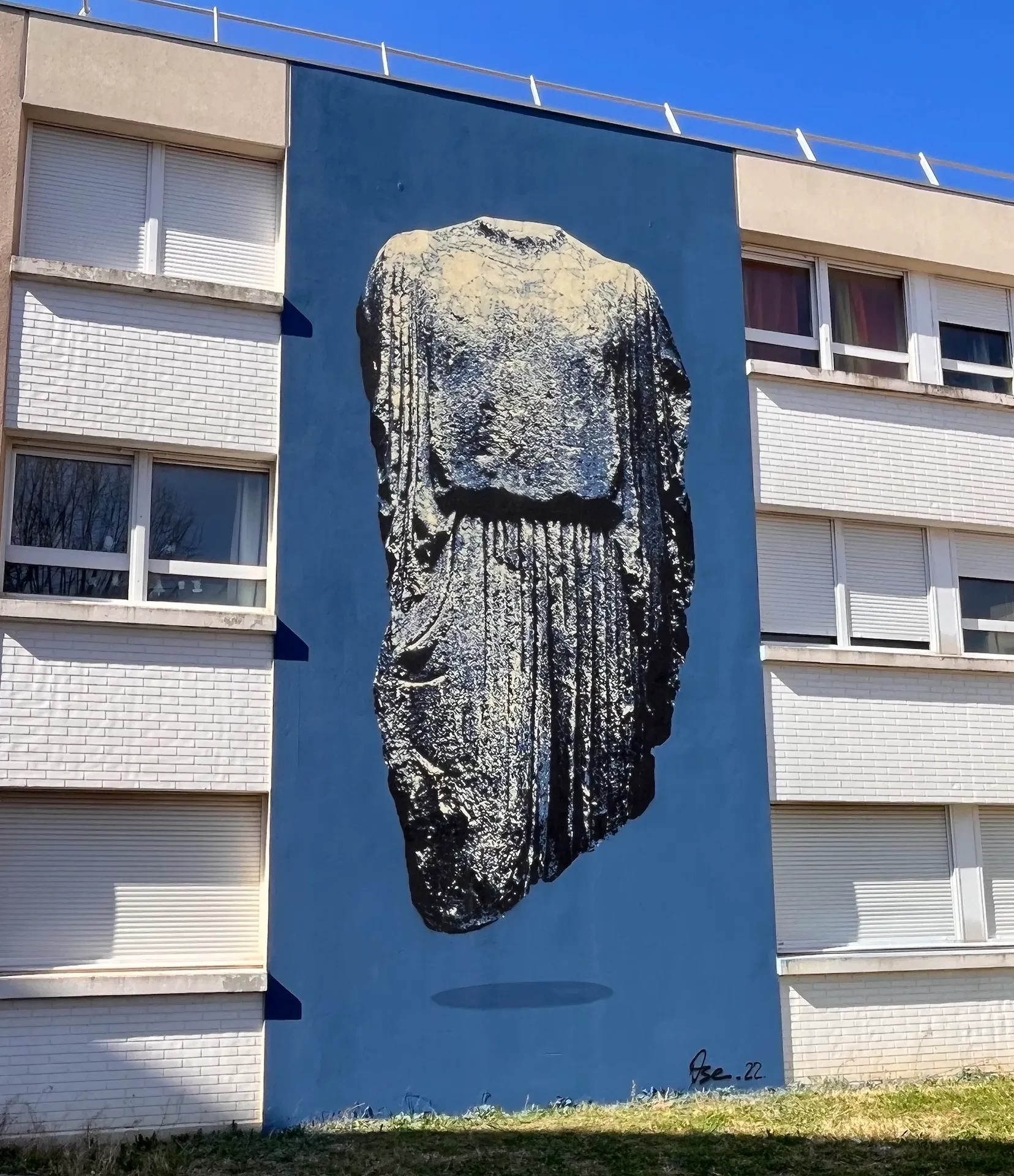 Photo d'une fresque sur fond bleu représentant un buste de type gallo-romain en pierre.