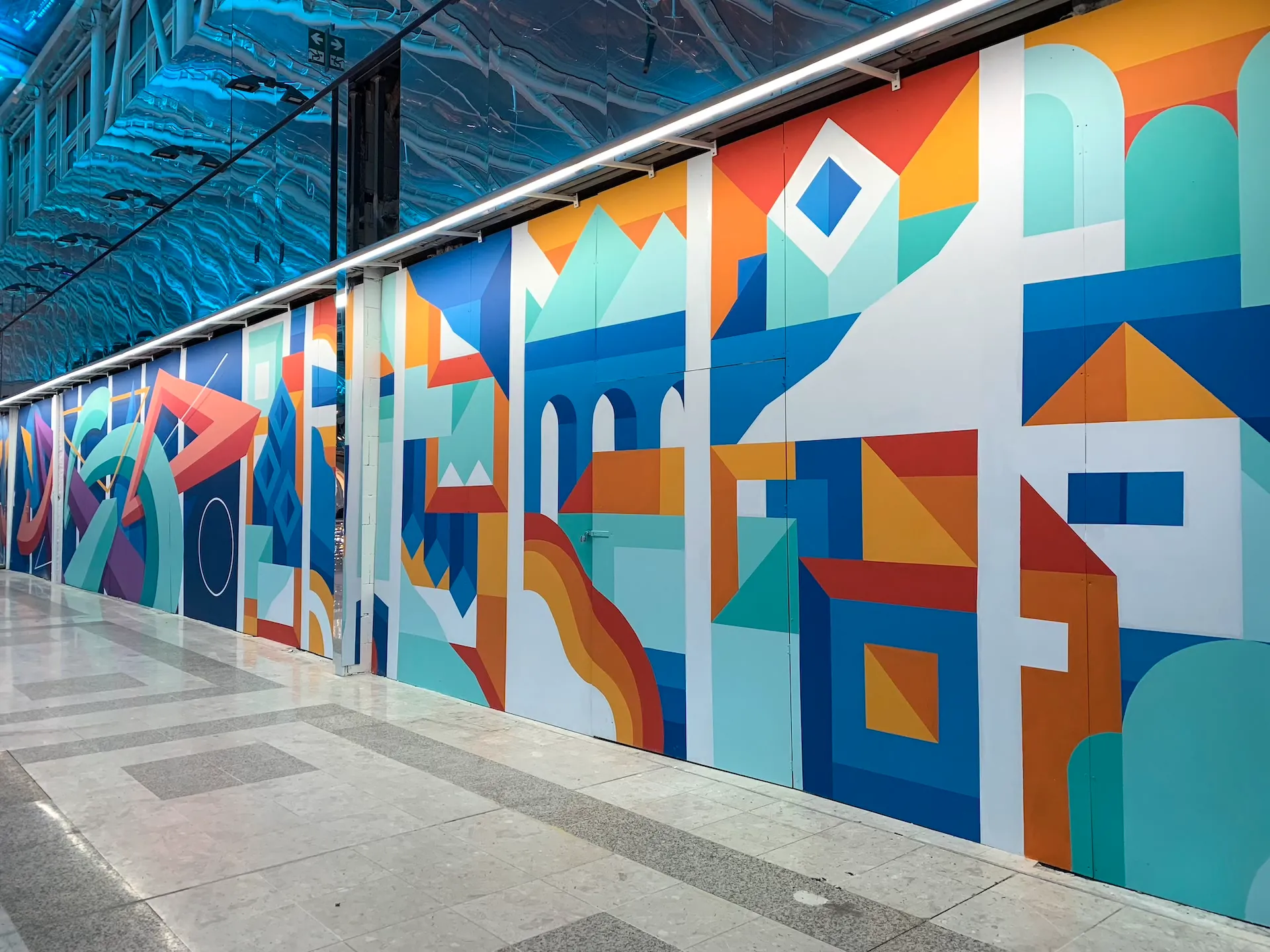 Vue en perspective d’un couloir orné de fresques abstraites colorées et de formes dynamiques.