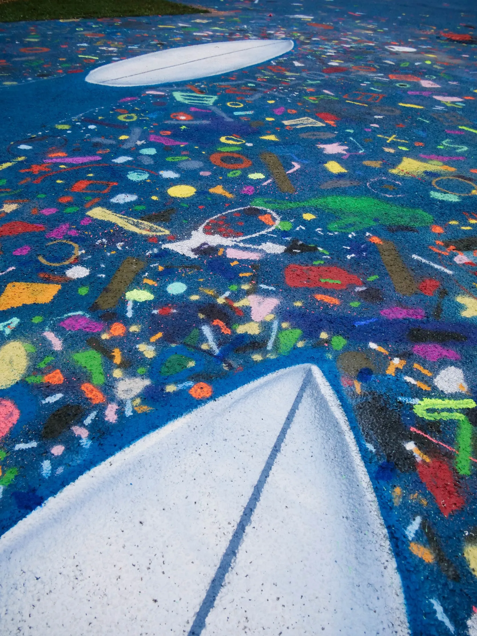 Vue en détails de la fresque où on devine le début d'une planche de surf et une multitude de confettis colorés autour.