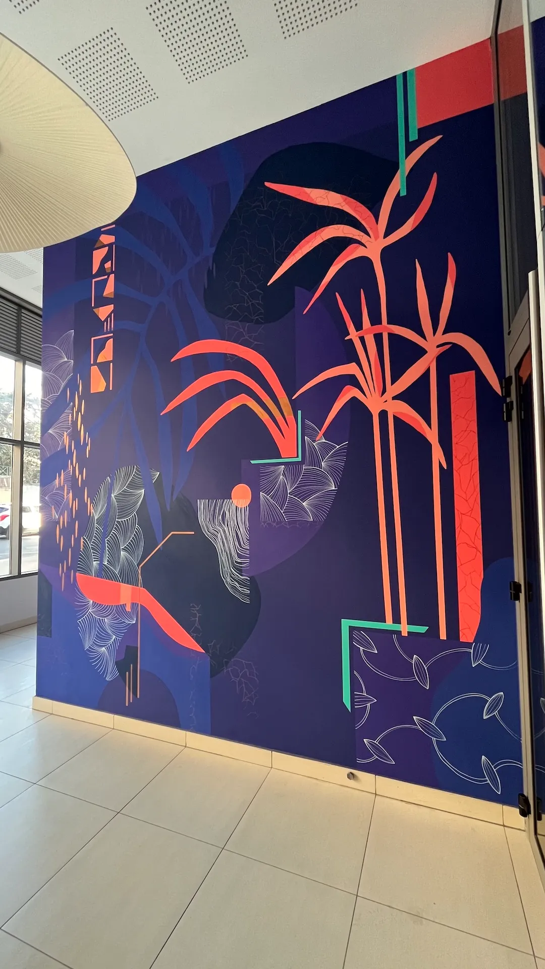 Vue de côté du mur du hall habillé d'une fresque bleue et rose.