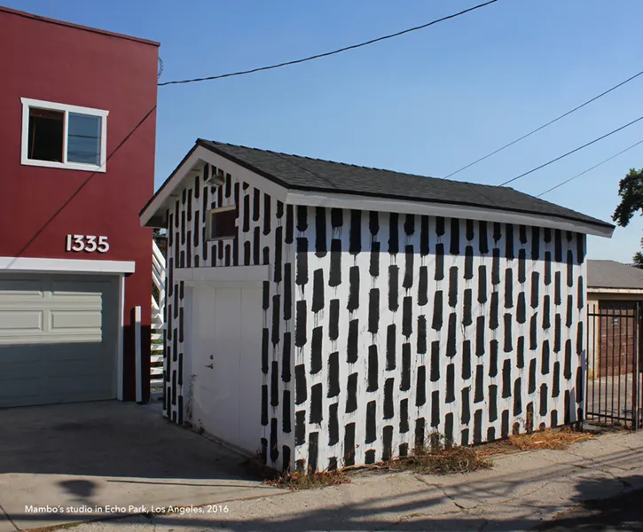 Fresque géométrique en noir et blanc sur la façade d’un bâtiment, composée de formes verticales répétitives.
