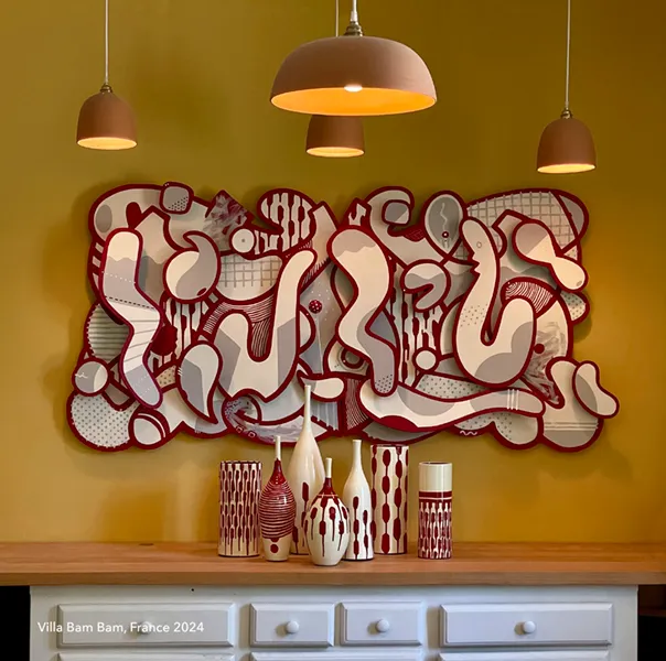 Peinture aux lignes ondulées rouges et beiges formant une structure abstraite, accrochée dans un intérieur moderne.