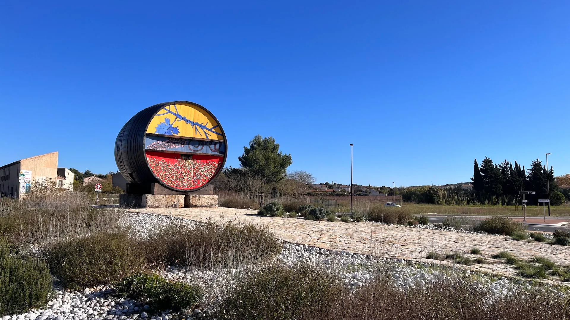 Œuvre artistique circulaire peinte aux couleurs vives, installée en bord de chemin dans un environnement naturel