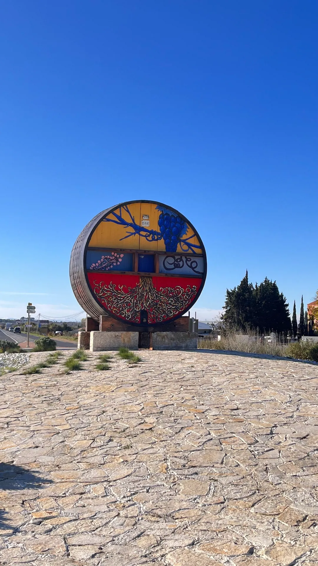 Œuvre d’art ronde peinte, posée sur un sol pavé, intégrée dans un espace extérieur sous un ciel dégagé