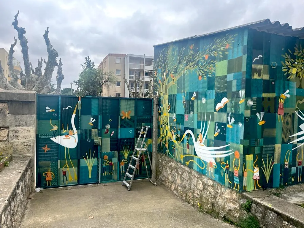 Fresque murale colorée aux motifs végétaux et géométriques, peinte sur un mur extérieur en milieu urbain