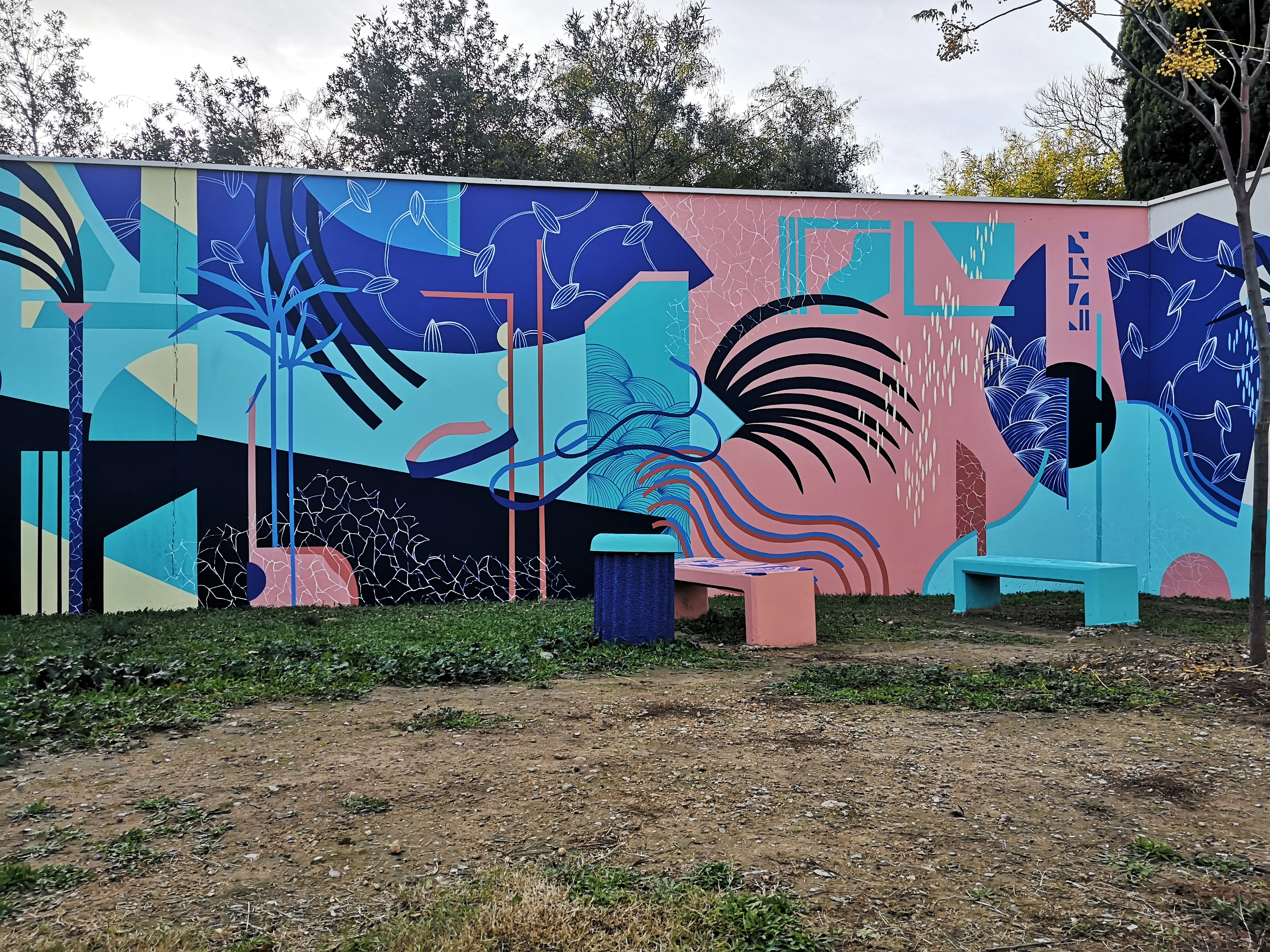 Vue large d’une fresque murale extérieure composée de formes géométriques et de couleurs vives