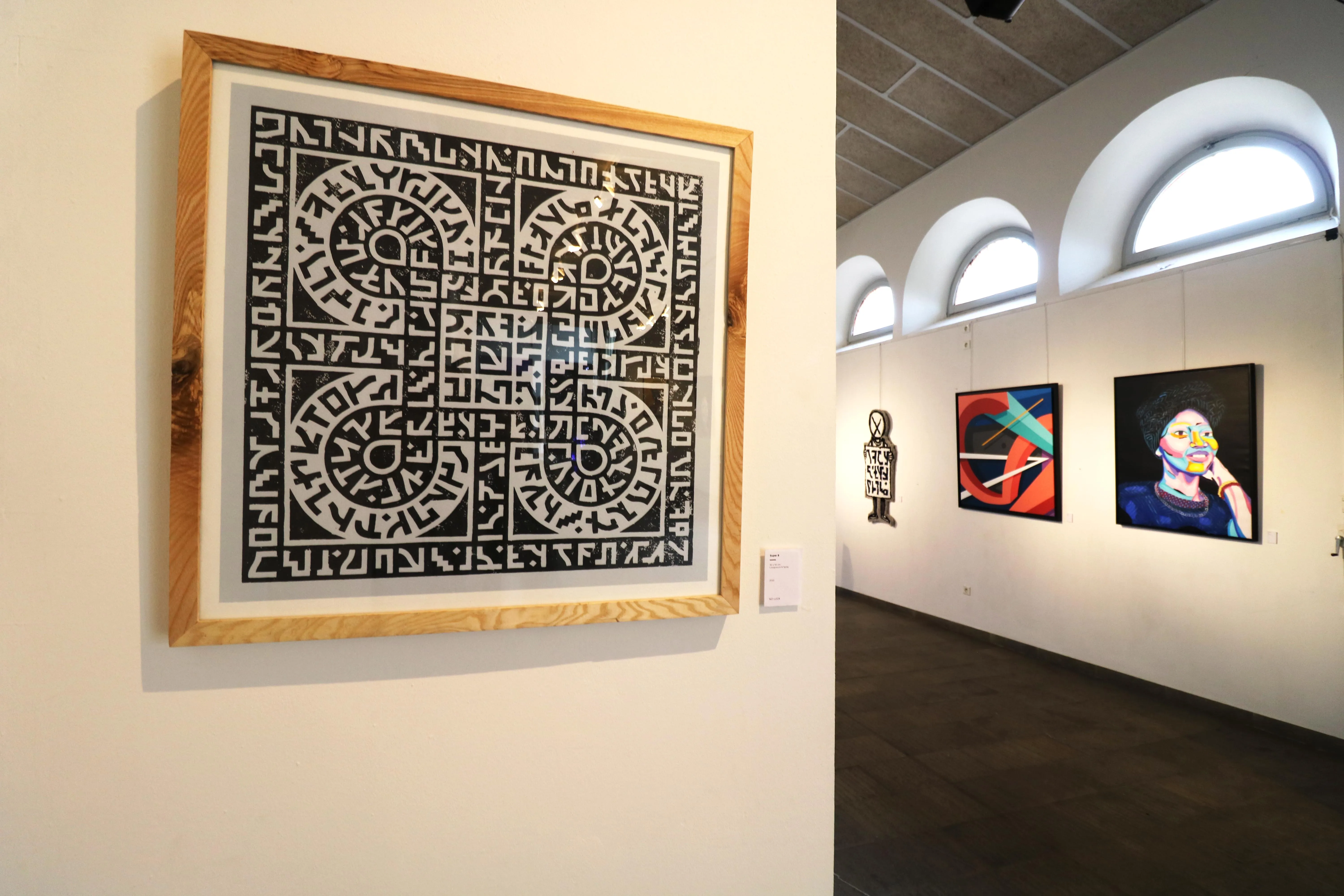 Vue d’exposition avec œuvres graphiques encadrées accrochées dans une galerie