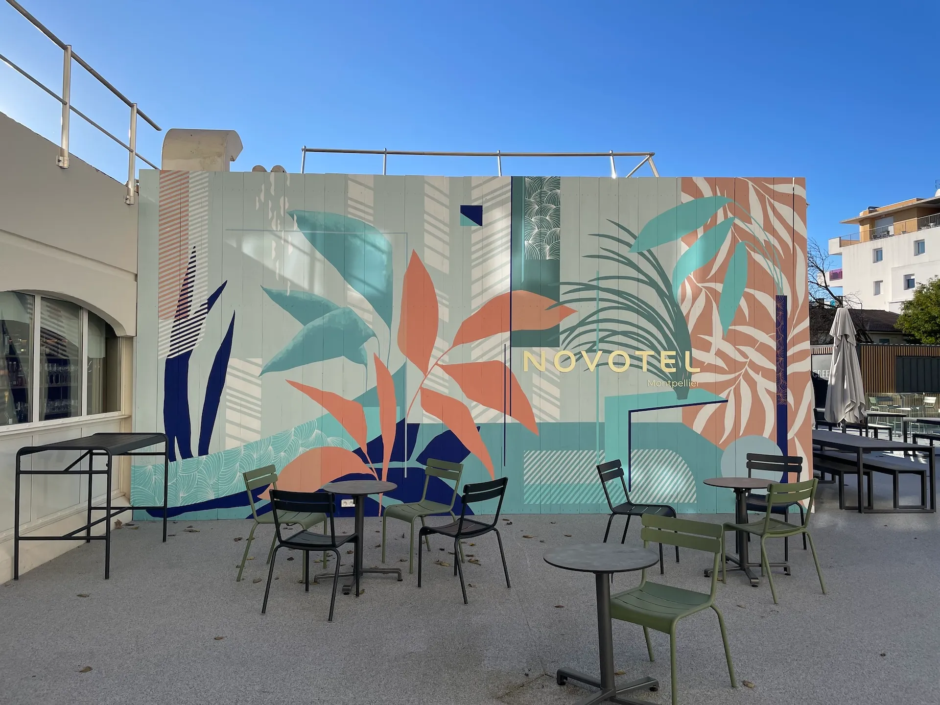 Fresque murale en extérieur en vert et corail, avec des éléments graphiques et végétaux.