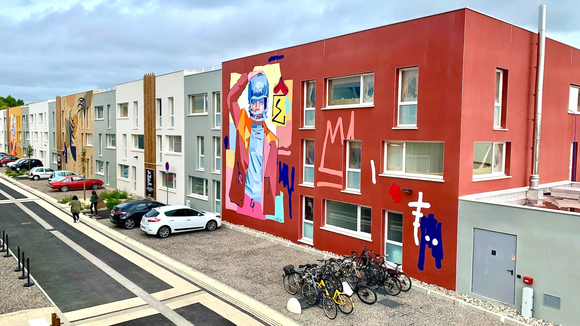 Vue en hauteur d'une enfilade de bâtiments de couleurs différentes avec une fresque sur une façade.