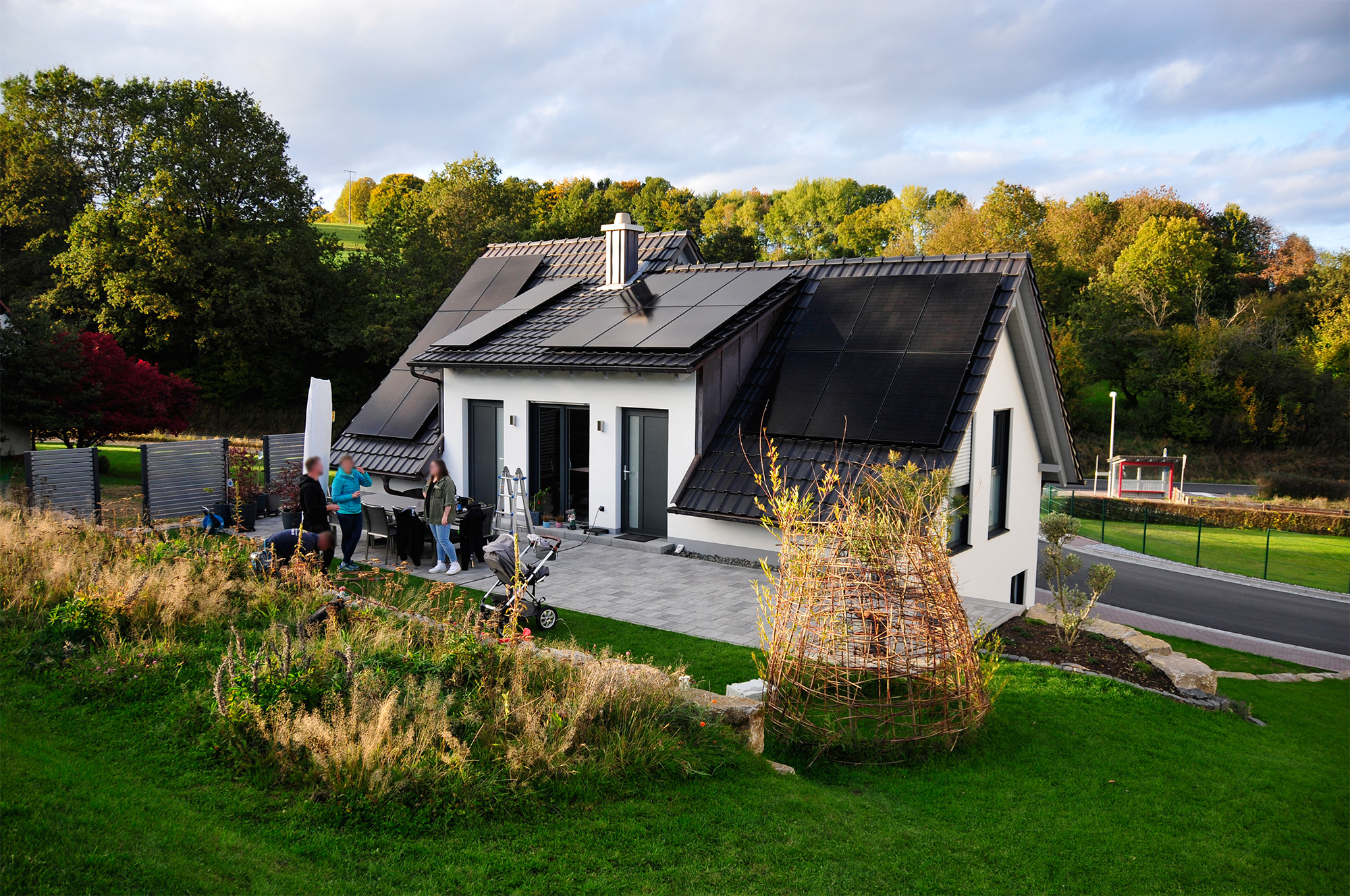 Ein alleinstehendes Zweifamilienhaus mit PV-Anlage. Arbeiter bringen die Solarmodule an.