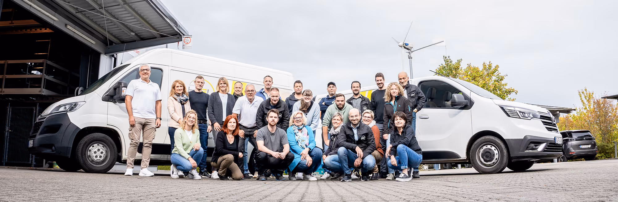 Das gesamte Team von HSL Solar. Alle stehen vor einem großen Gebäude und halten ihre Arme in der Luft. 