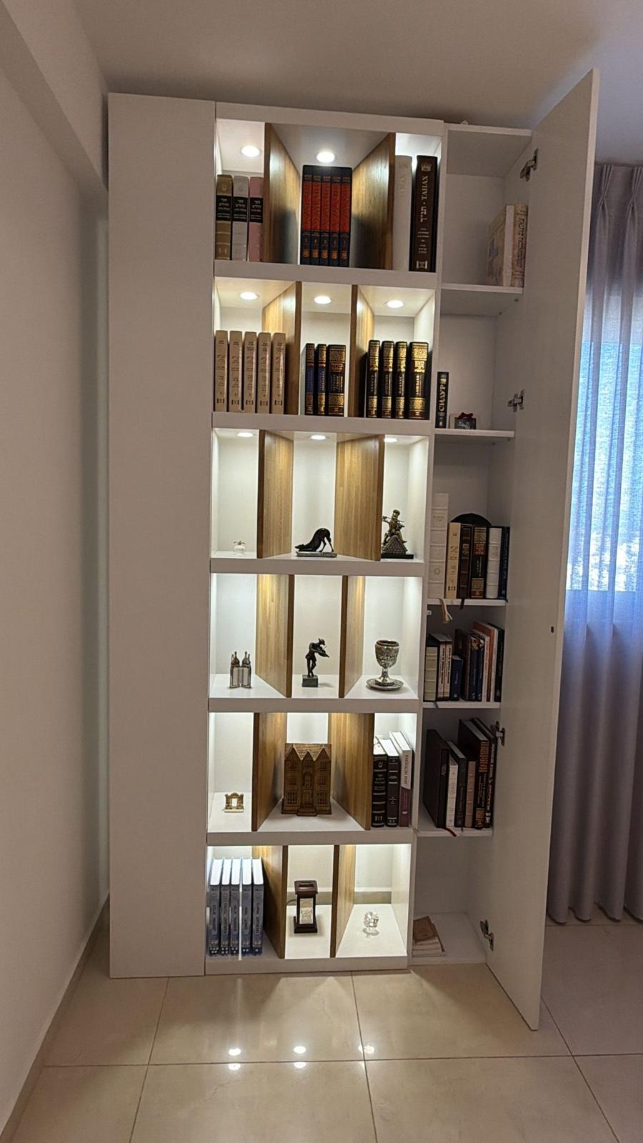 A modern-style bookcase made of natural wood with integrated interior lighting that highlights sacred books and Judaica items. Available in custom sizes.