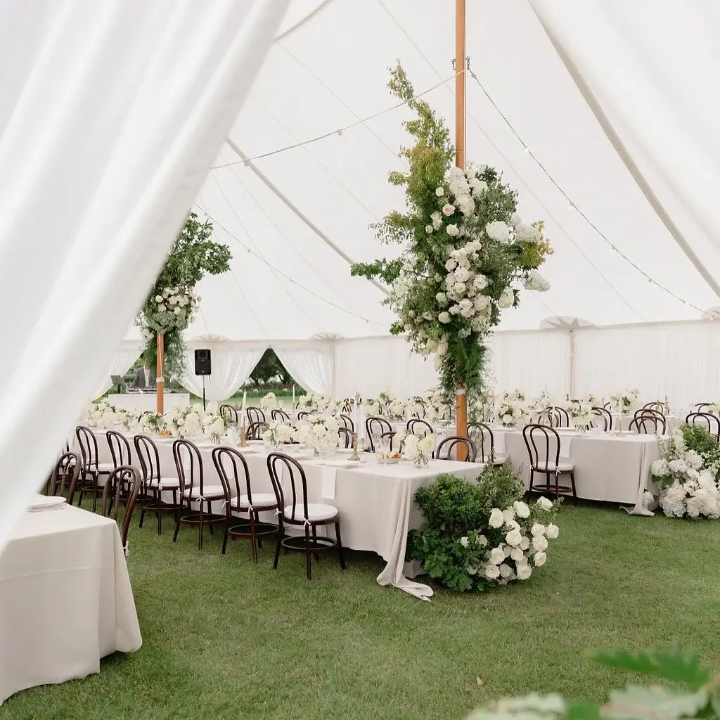 Elegant marquee event setup with long white tables, bentwood chairs, and floral arrangements for a Penrith Party Hire event