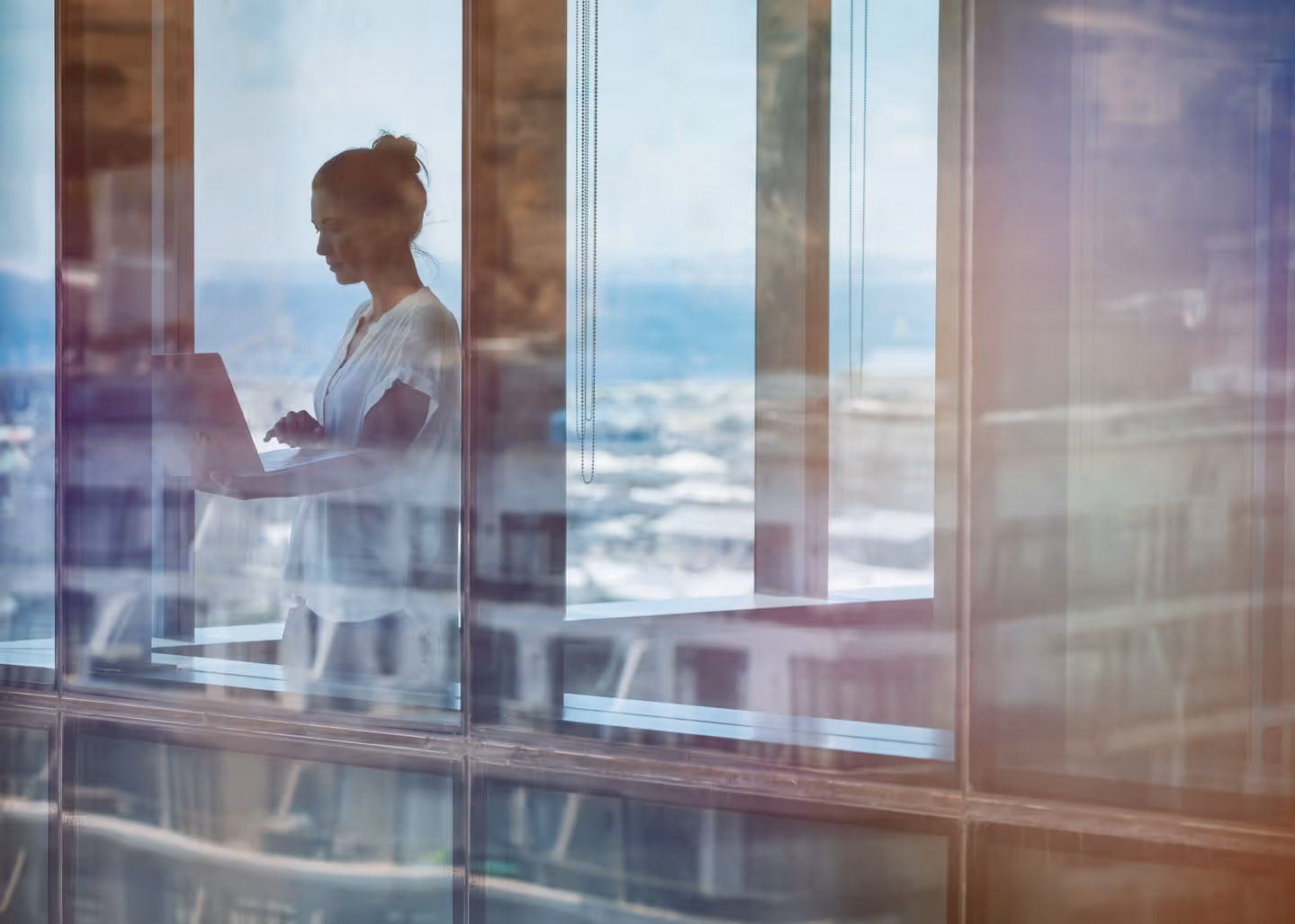 Woman near a window looking at a laptop screen