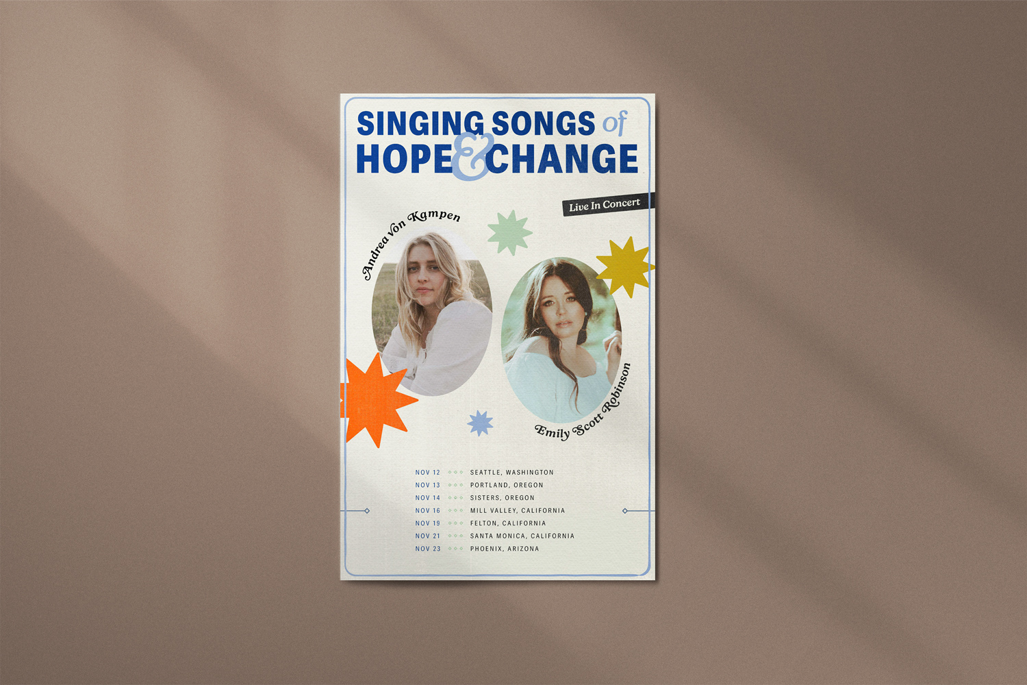 A mocha-colored wall, featuring the tour poster for "Singing Songs of Hope & Change". The post features the title in styled navy and light blue text, with a text accent reading "Live in Concert". In two ovals, photos of Andrea von Kampen and Emily Scott Robinson featured in the middle among stars in muted greens, yellows, oranges and blues. At the bottom, their November show schedule is listed.