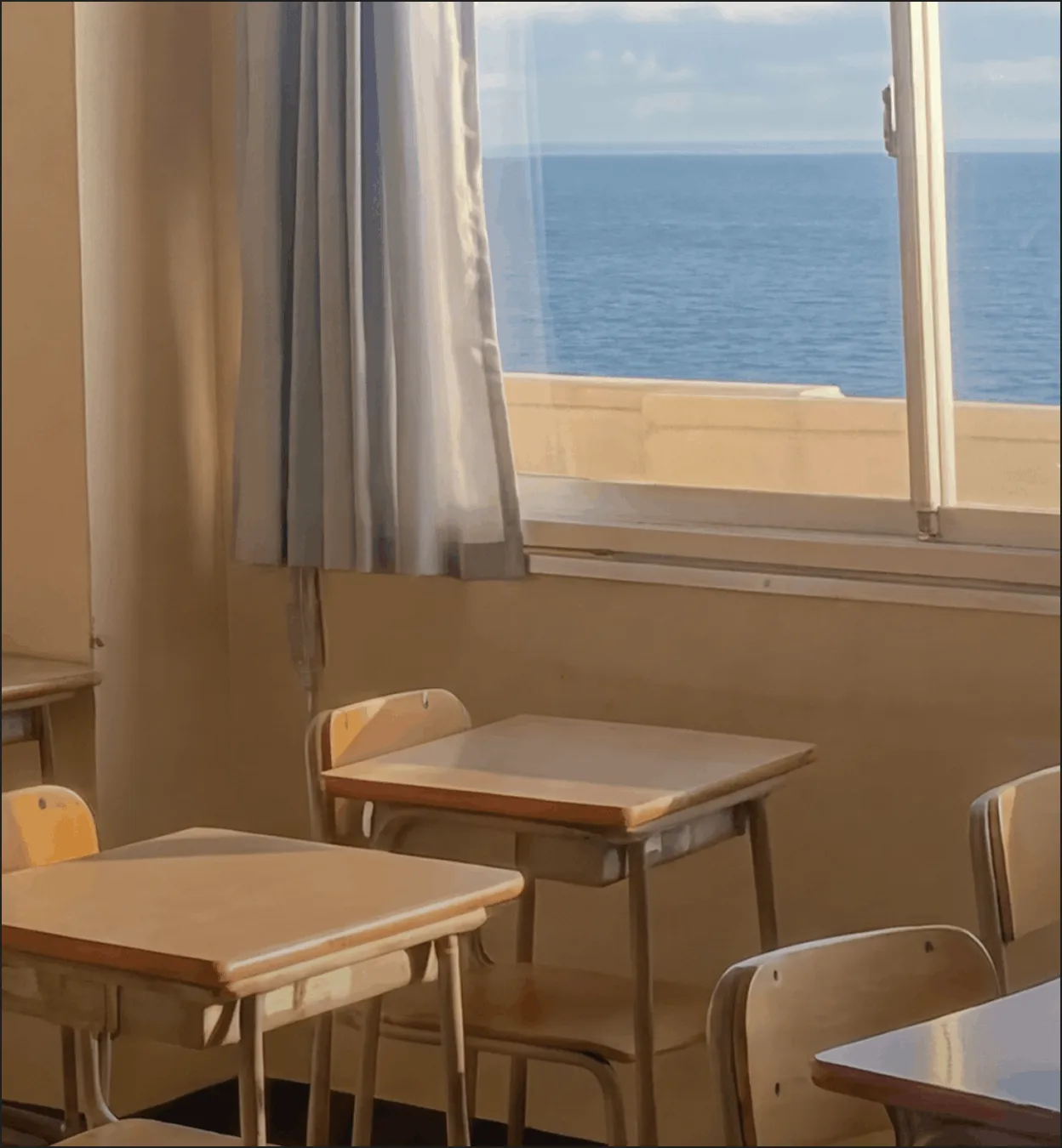 Empty classroom with wooden desks and chairs near a window showing a sea view.