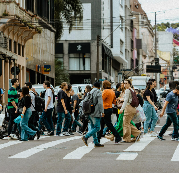 Crowd of people crossing a city street at a crosswalk surrounded by buildings.