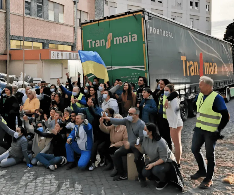 Grupo com bandeira da Ucrânia ao lado de camião da Transmaia