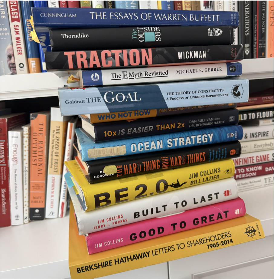 Stack of business books about operations, strategy, leadership, and management on a bookshelf
