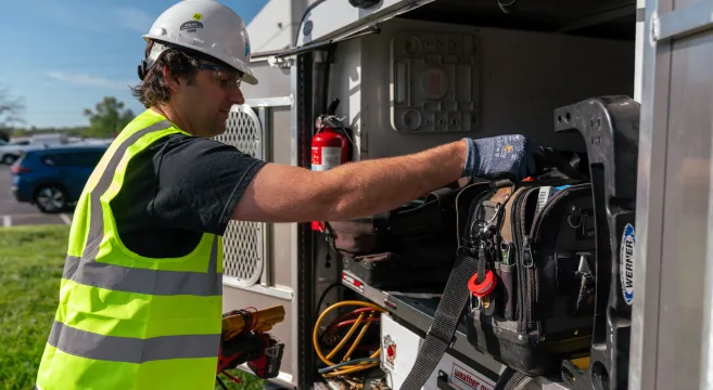 Worker retrieving tools from truck.