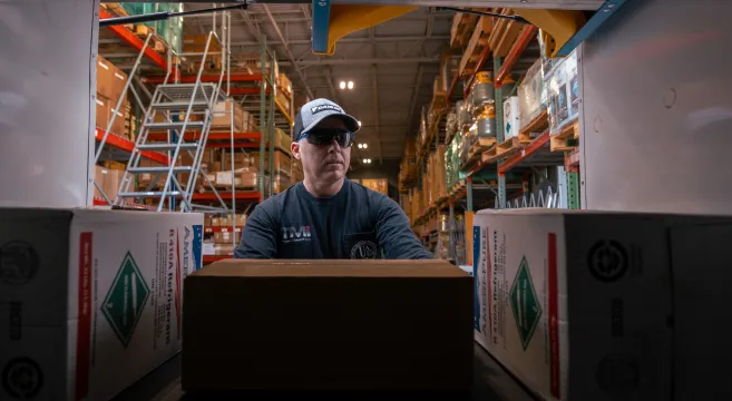 Man pushing box in warehouse.