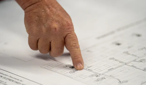 Finger pointing at blueprints.