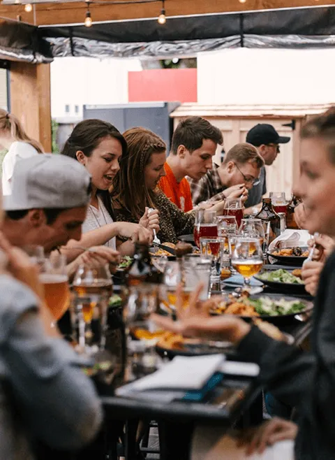 Diners savoring food and drinks together at a table in the welcoming atmosphere of Ashland Brewing Company.