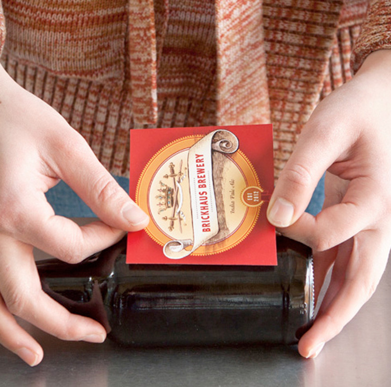 hands applying a beer label on a bottle for our printing services (design in the label)