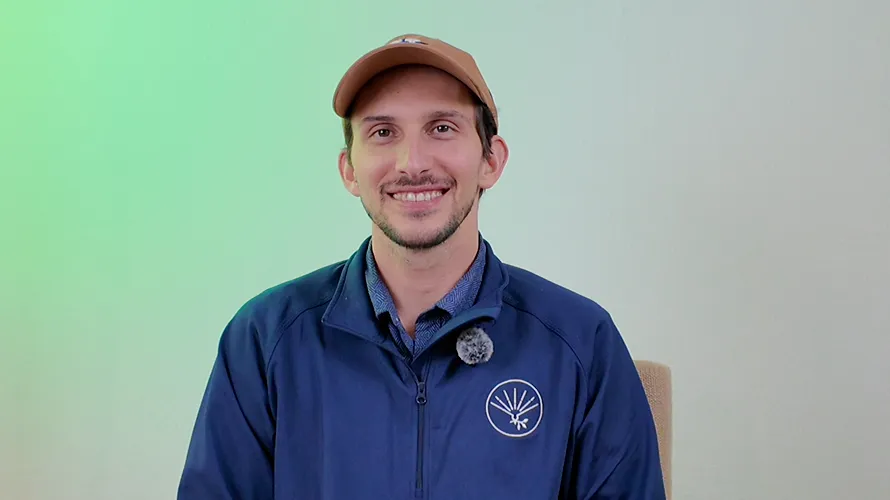Dilan in a cap and navy jacket smiling during his video interview