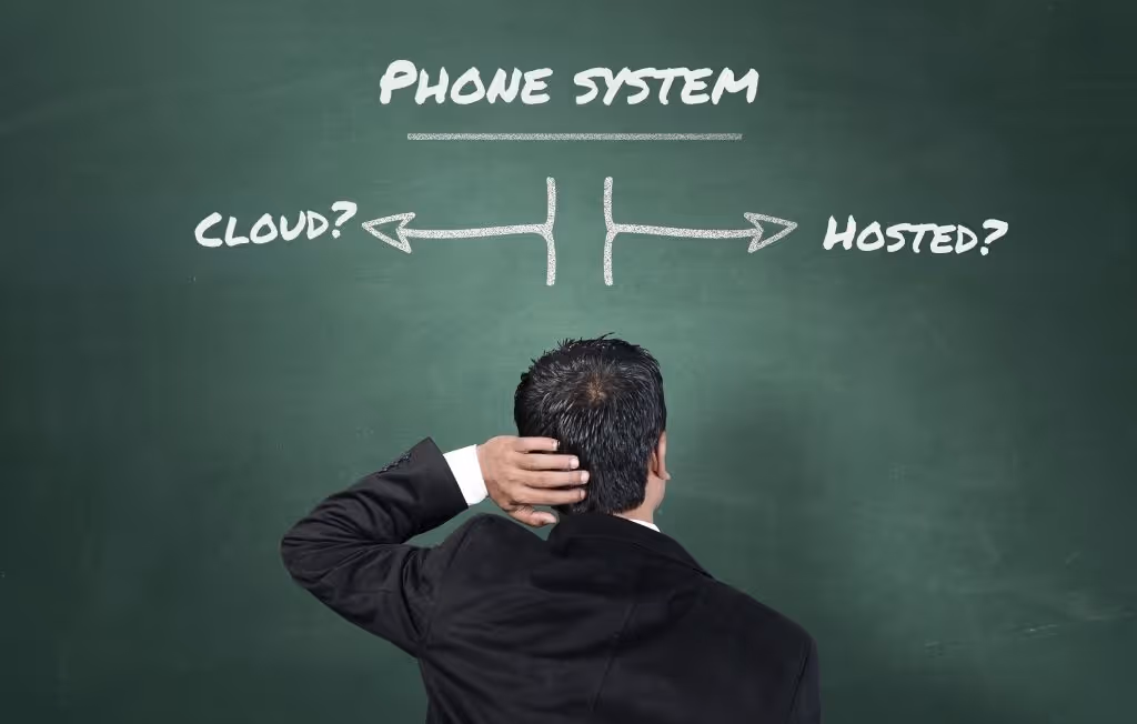 Confused hotel operator standing in front of chalkboard comparing cloud-based PBX vs hosted PBX phone system options.