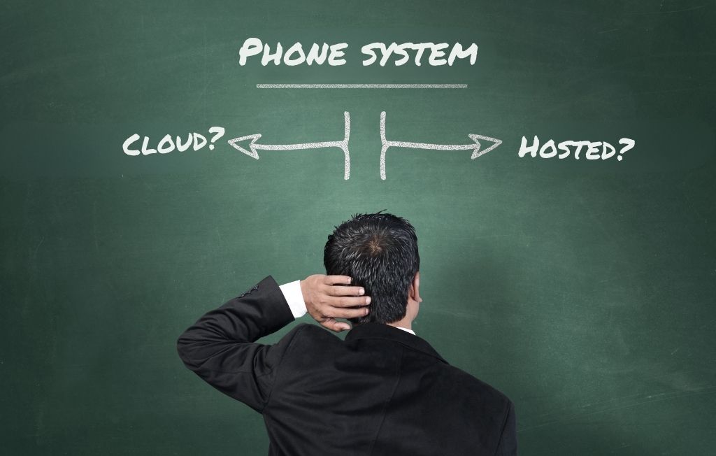 Confused hotel operator standing in front of chalkboard comparing cloud-based PBX vs hosted PBX phone system options.