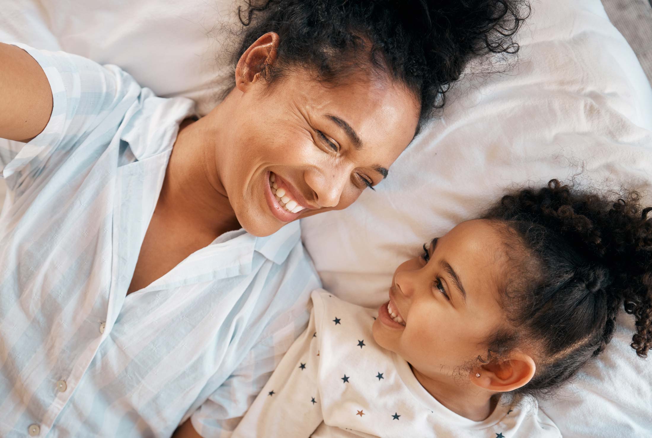 Young mother laughing with her daughter on a bed