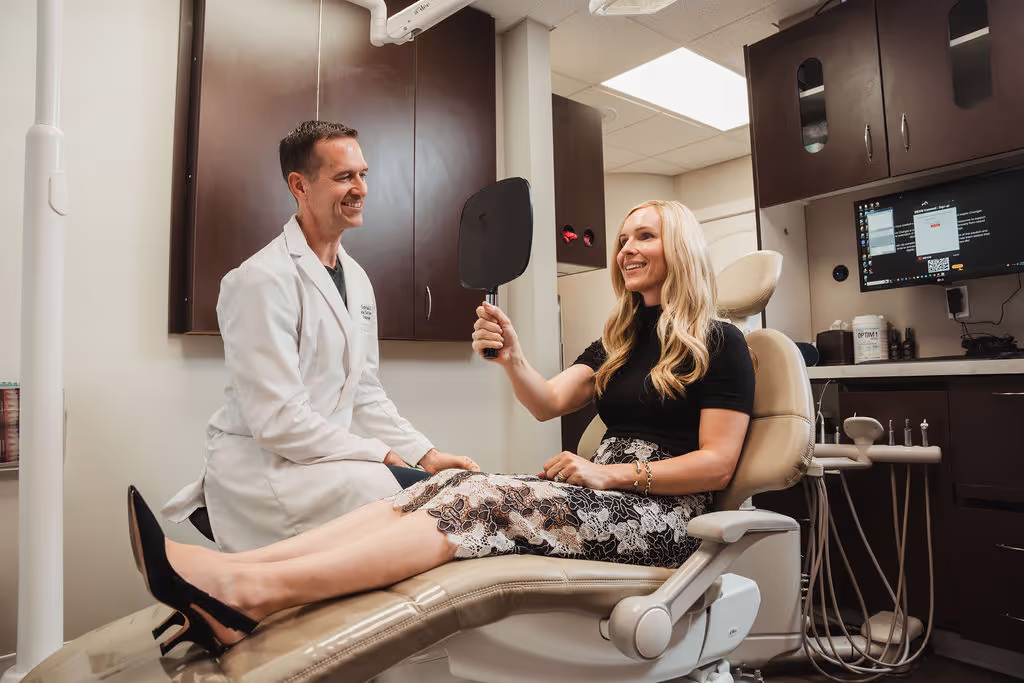 Blonde patient smiling while holding a mirror.