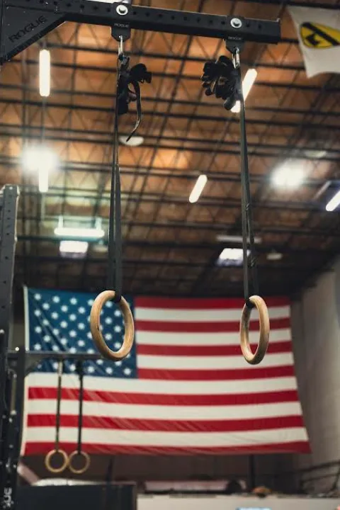 A woman lifts a barbell in a CrossFit gym at NOEQL Training Co. in Tampa, FL, showcasing strength and determination.