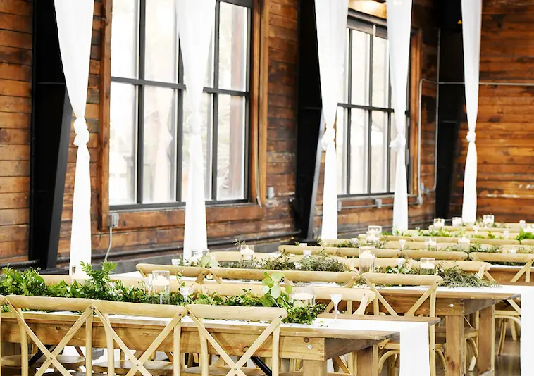 Wedding tables set with fresh greenery garlands and candles